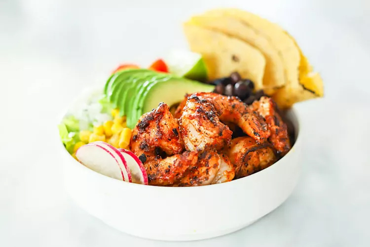 High-protein shrimp taco bowl with rice, avocado, black beans, corn, tomatoes, lime, and fresh cilantro