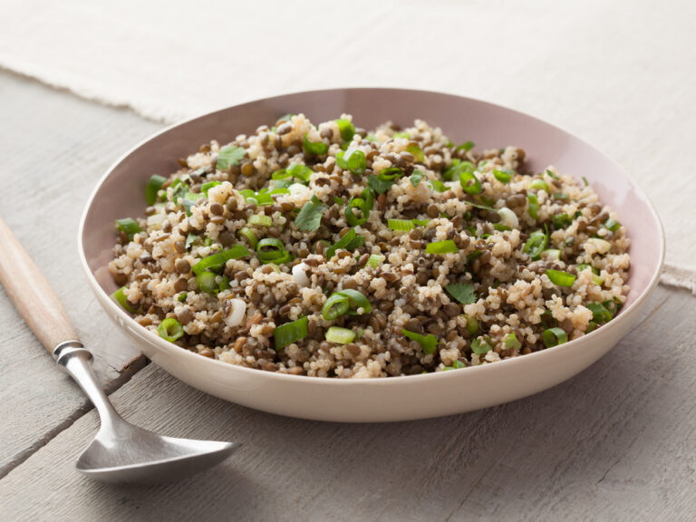 High-protein vegan lentil quinoa salad with green onions and fresh herbs in a bowl.