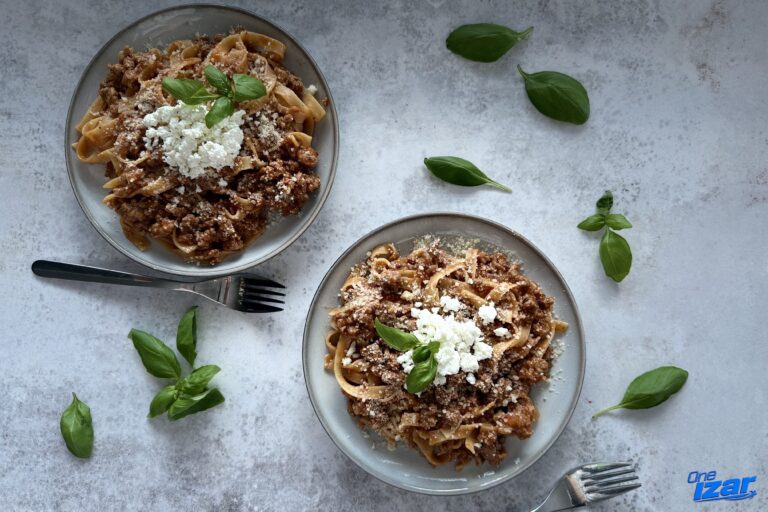 High-protein creamy turkey bolognese pasta with cottage cheese, parmesan and fresh basil, served in two plates with forks
